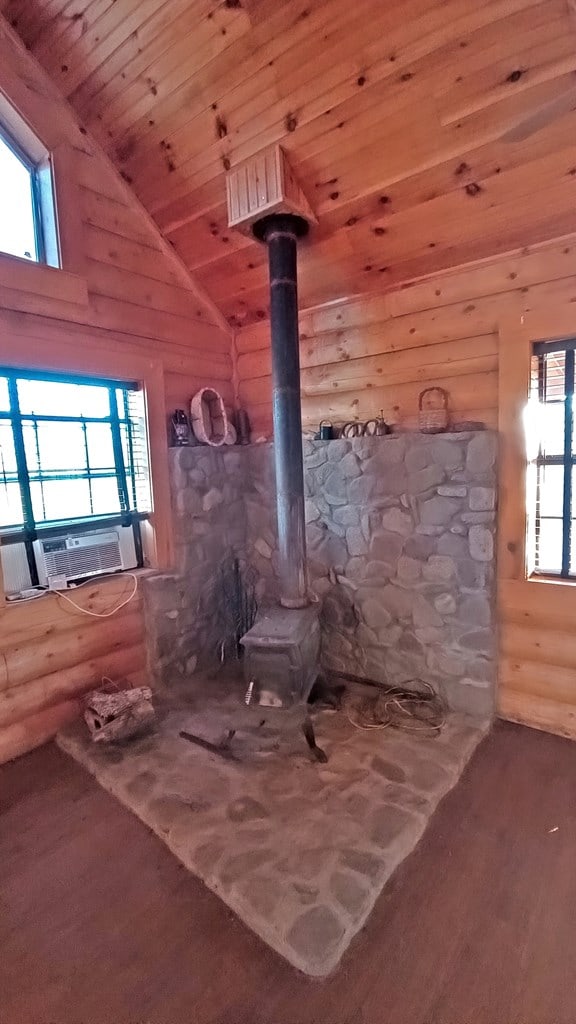 misc room featuring wood ceiling, cooling unit, wood-type flooring, a wood stove, and lofted ceiling