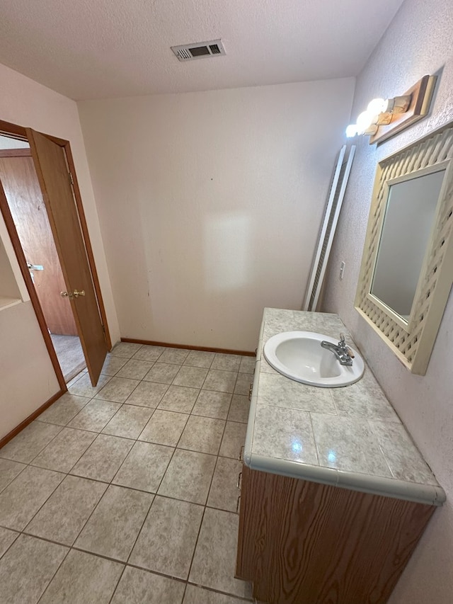 bathroom featuring vanity, tile patterned floors, and a textured ceiling