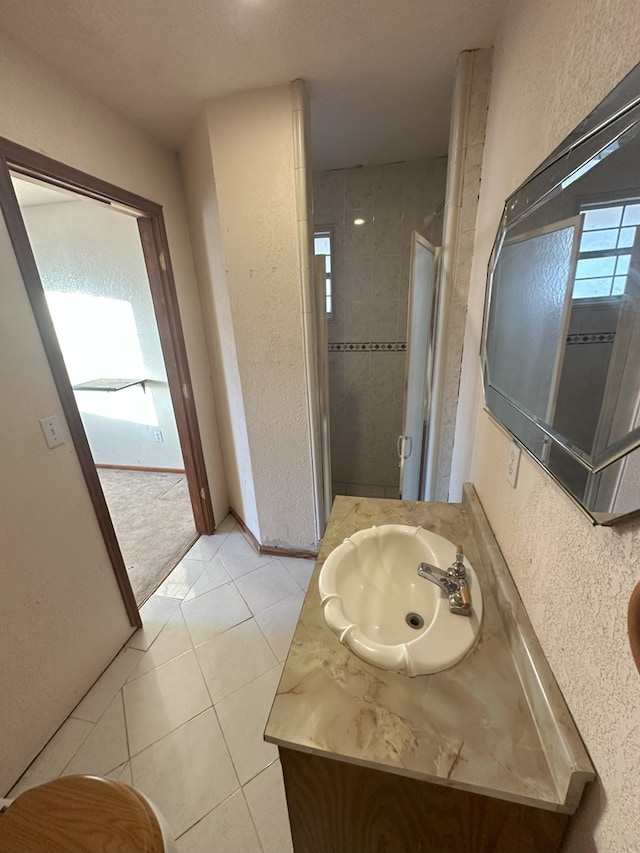 bathroom featuring tiled shower, vanity, and tile patterned flooring