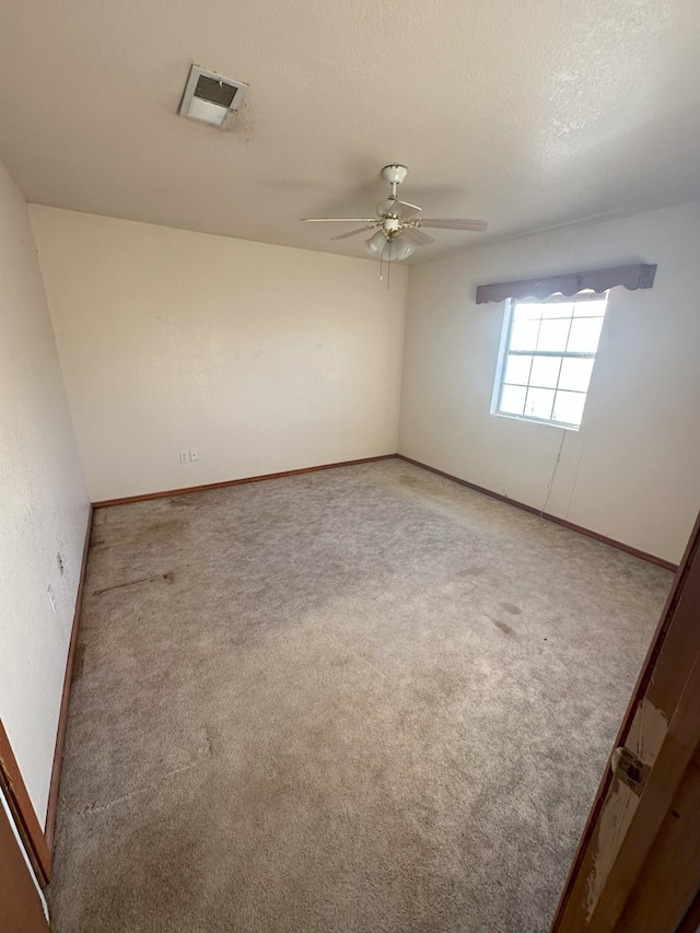 carpeted spare room featuring ceiling fan and a textured ceiling