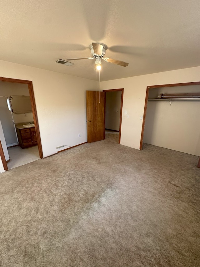 unfurnished bedroom featuring ensuite bathroom, ceiling fan, light carpet, a textured ceiling, and a closet