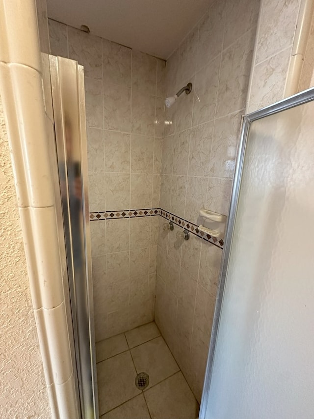 bathroom with a tile shower and tile patterned floors