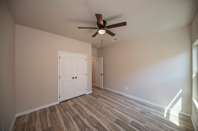 unfurnished bedroom featuring a closet, light hardwood / wood-style flooring, and ceiling fan