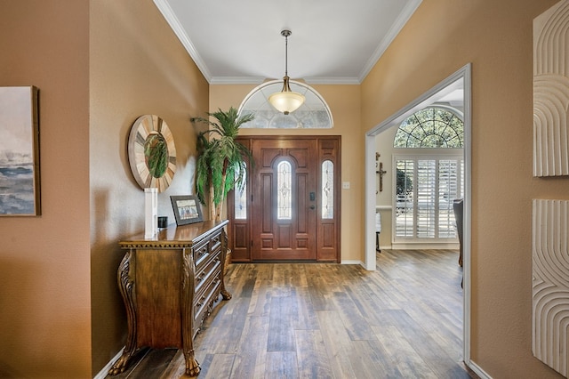 foyer entrance with ornamental molding, baseboards, and wood finished floors