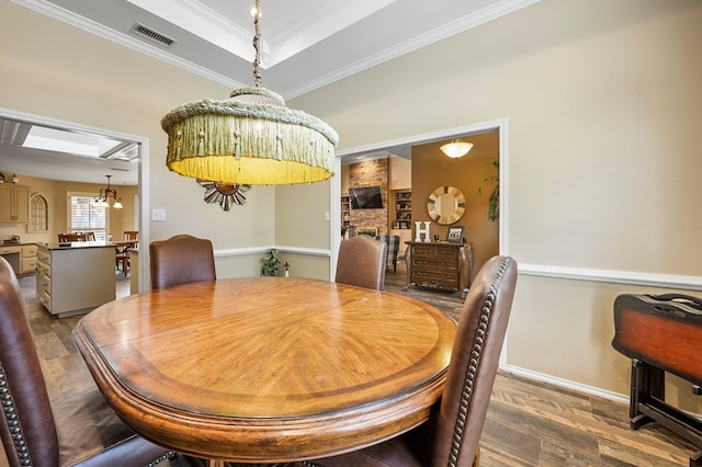 dining room featuring ornamental molding, dark wood-style flooring, a raised ceiling, and visible vents