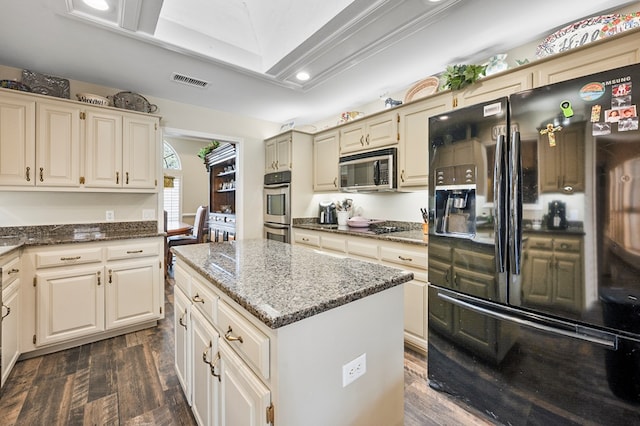 kitchen with visible vents, dark wood finished floors, dark stone counters, a center island, and stainless steel appliances