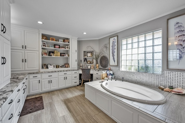 bathroom with ornamental molding, recessed lighting, and a bath