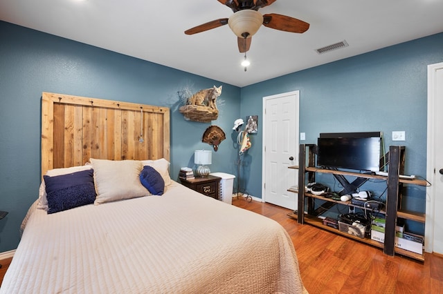 bedroom with baseboards, wood finished floors, visible vents, and a ceiling fan