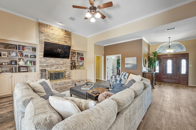 living area with ornamental molding, hardwood / wood-style floors, a brick fireplace, and visible vents