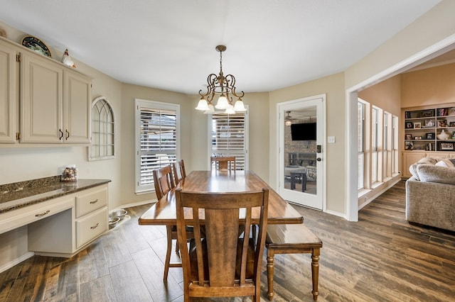 dining room with a chandelier, built in study area, dark wood finished floors, and baseboards