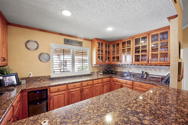 kitchen featuring crown molding, a textured ceiling, glass insert cabinets, and a sink