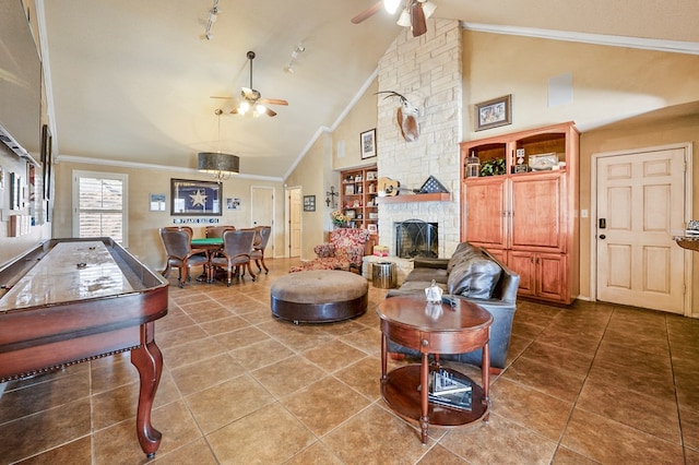 tiled living room featuring high vaulted ceiling, ornamental molding, a ceiling fan, and a stone fireplace