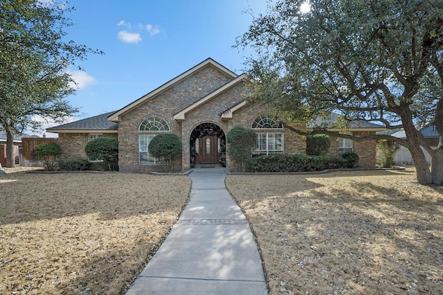 ranch-style home featuring brick siding and fence