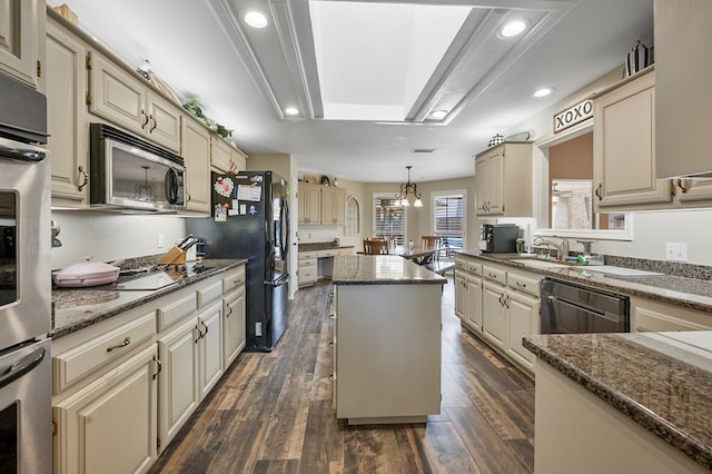 kitchen featuring black appliances, cream cabinets, a kitchen island, and dark wood finished floors