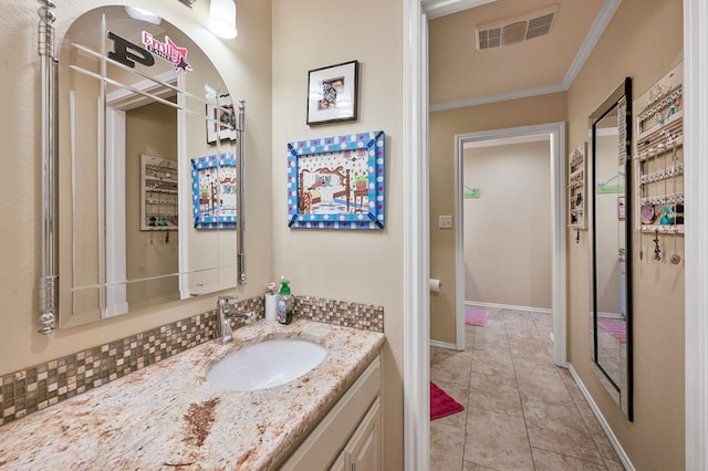 bathroom featuring tile patterned flooring, vanity, baseboards, visible vents, and crown molding