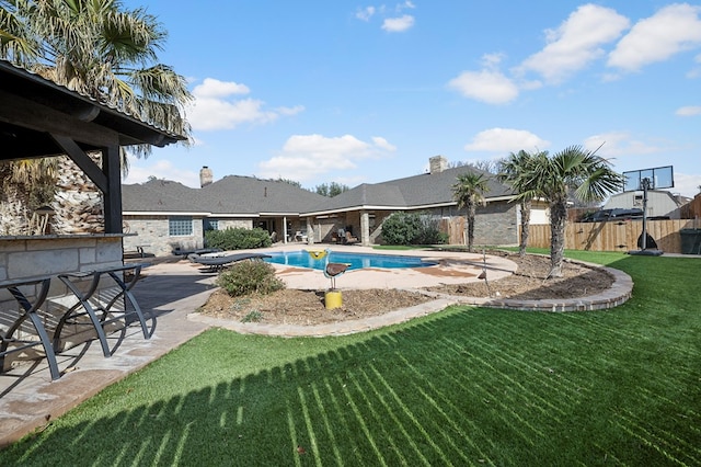 view of swimming pool with a fenced in pool, outdoor dry bar, fence, a yard, and a patio area