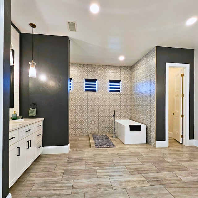 full bathroom featuring a tub to relax in, visible vents, vanity, a walk in shower, and recessed lighting