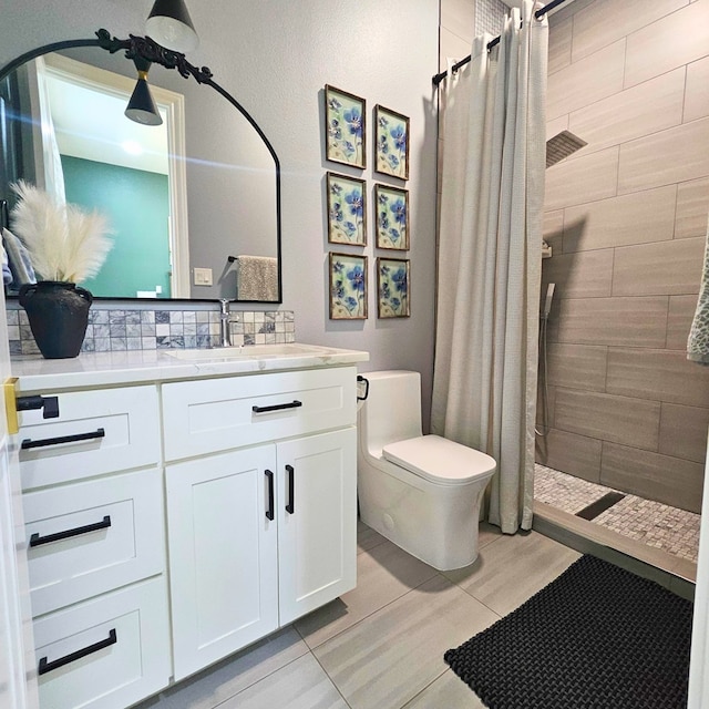 full bathroom featuring toilet, a tile shower, and vanity