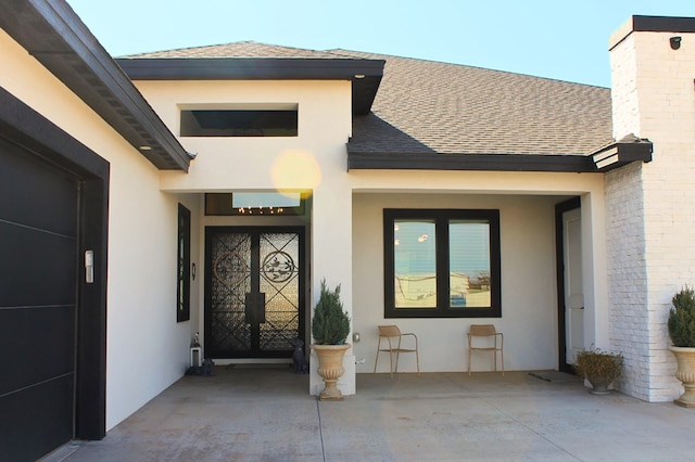 doorway to property with a shingled roof and stucco siding