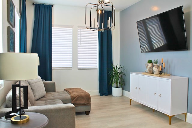 living area with a notable chandelier, light wood-style flooring, and baseboards