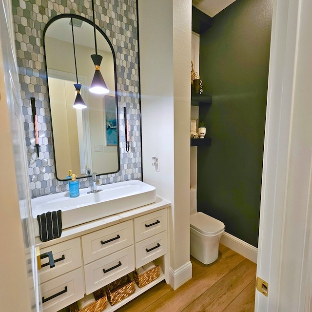 bathroom featuring baseboards, vanity, toilet, and wood finished floors