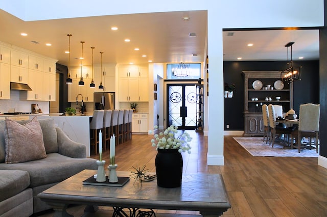 living room featuring an inviting chandelier, baseboards, dark wood-type flooring, and recessed lighting