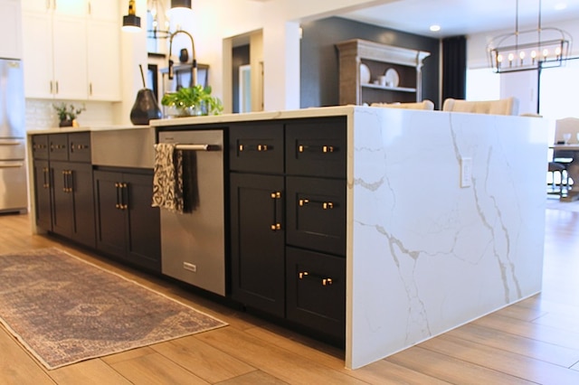 kitchen with decorative light fixtures, light wood-type flooring, white cabinetry, and dark cabinets