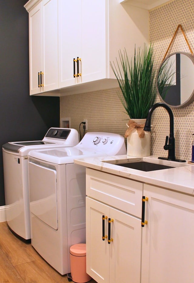 washroom featuring light wood-style floors, cabinet space, a sink, and washing machine and clothes dryer