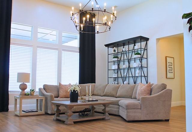 living room with a towering ceiling, baseboards, and wood finished floors