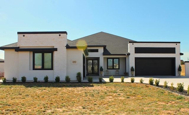 view of front facade with a front yard, driveway, an attached garage, and stucco siding