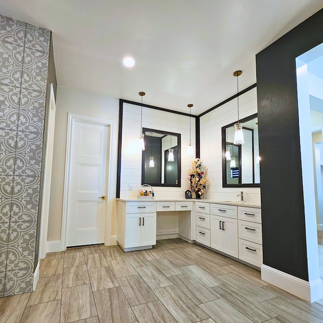 bathroom with wood tiled floor, a sink, baseboards, and double vanity