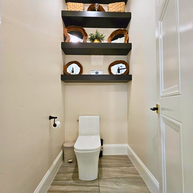 bathroom with toilet, baseboards, and wood finished floors