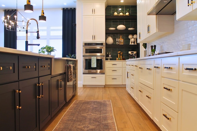 kitchen featuring backsplash, double oven, white cabinetry, light wood-type flooring, and under cabinet range hood