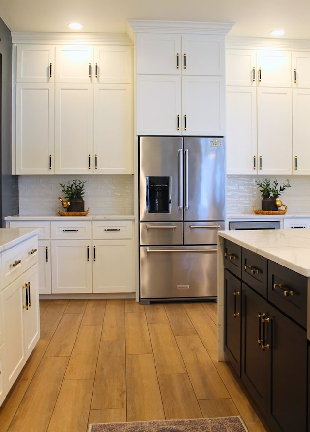 kitchen featuring white cabinets, high quality fridge, backsplash, and light wood finished floors