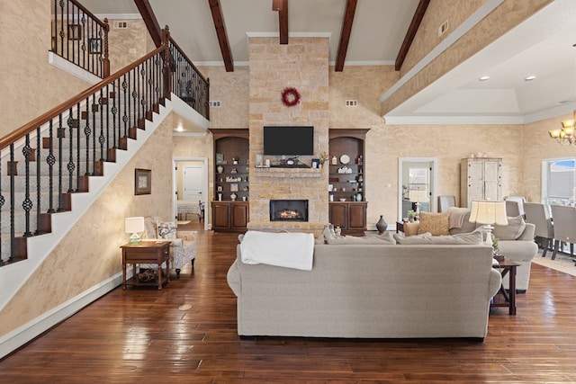 living room featuring dark hardwood / wood-style flooring, a towering ceiling, beamed ceiling, a notable chandelier, and a fireplace