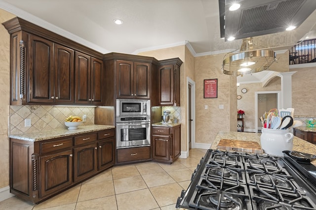 kitchen with dark brown cabinetry, light stone counters, ornamental molding, and appliances with stainless steel finishes