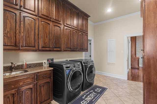 laundry room with cabinets, ornamental molding, sink, light tile patterned floors, and washing machine and dryer