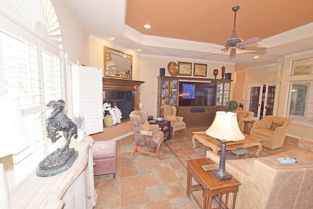 living room featuring ornamental molding, a raised ceiling, and ceiling fan