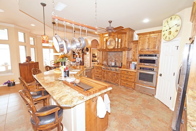 kitchen with pendant lighting, sink, a kitchen breakfast bar, light stone counters, and stainless steel appliances