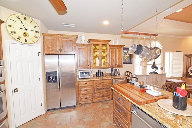 kitchen featuring crown molding, ceiling fan, stainless steel appliances, and light stone countertops