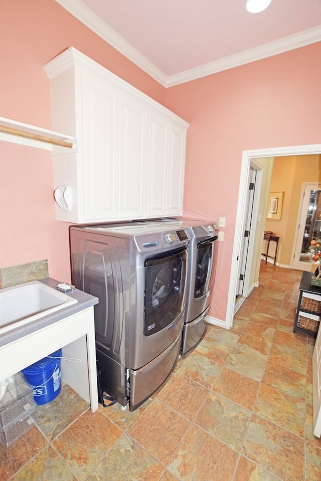 washroom featuring ornamental molding, cabinets, and washing machine and clothes dryer