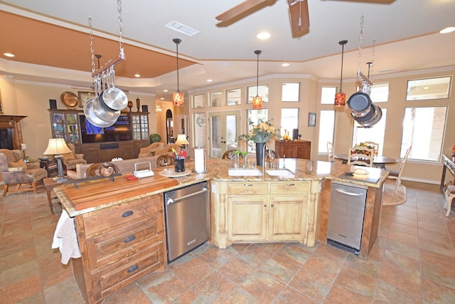 kitchen featuring ceiling fan, light stone counters, ornamental molding, an island with sink, and stainless steel dishwasher