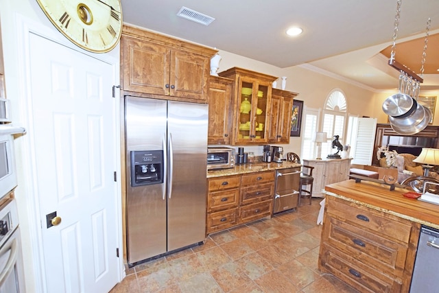 kitchen with stainless steel appliances, crown molding, and light stone counters