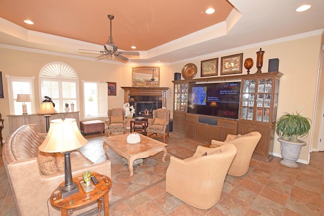 living room with ornamental molding, ceiling fan, and a tray ceiling