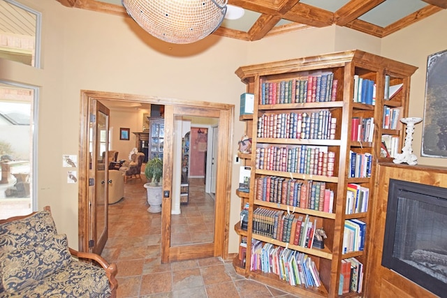 living area featuring beamed ceiling, ornamental molding, coffered ceiling, and a towering ceiling