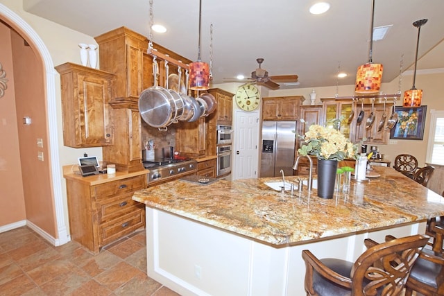 kitchen featuring hanging light fixtures, light stone countertops, a center island with sink, and stainless steel fridge with ice dispenser