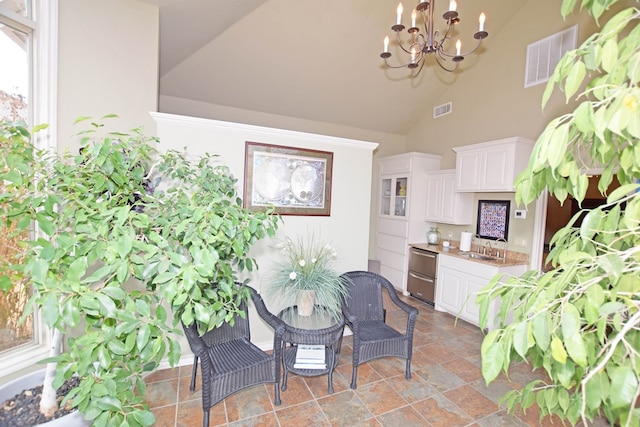 interior space featuring white cabinetry, high vaulted ceiling, an inviting chandelier, and sink