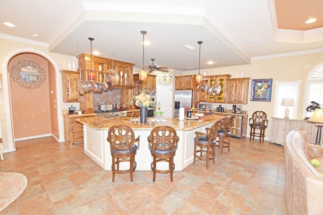 kitchen with pendant lighting, a kitchen breakfast bar, light stone countertops, and a kitchen island with sink