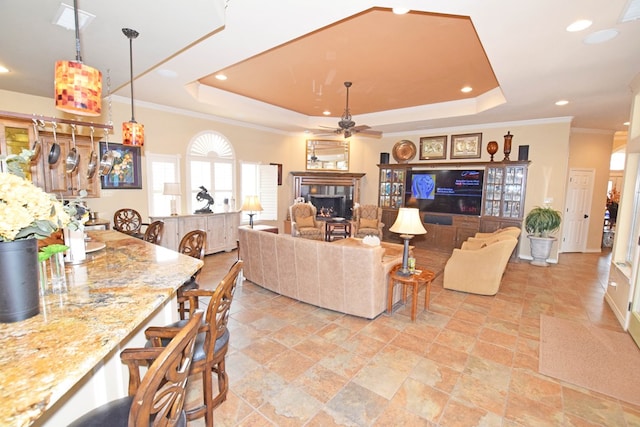 living room with crown molding, ceiling fan, and a raised ceiling