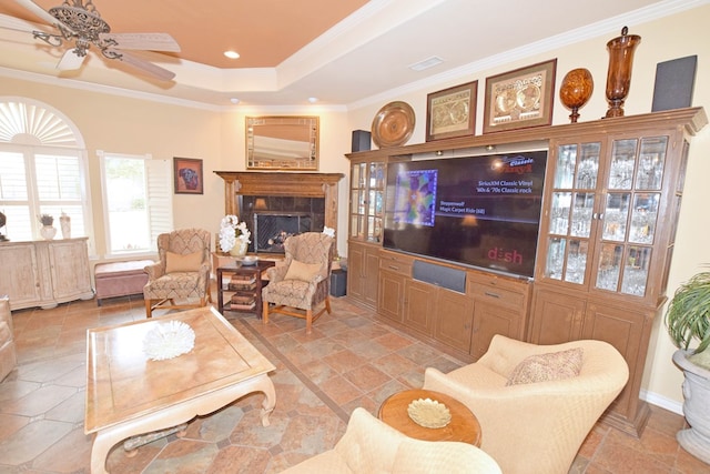 living room with a raised ceiling, crown molding, and ceiling fan